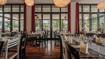 A restaurant with multiple dining tables, chairs, and hanging pendant lights.