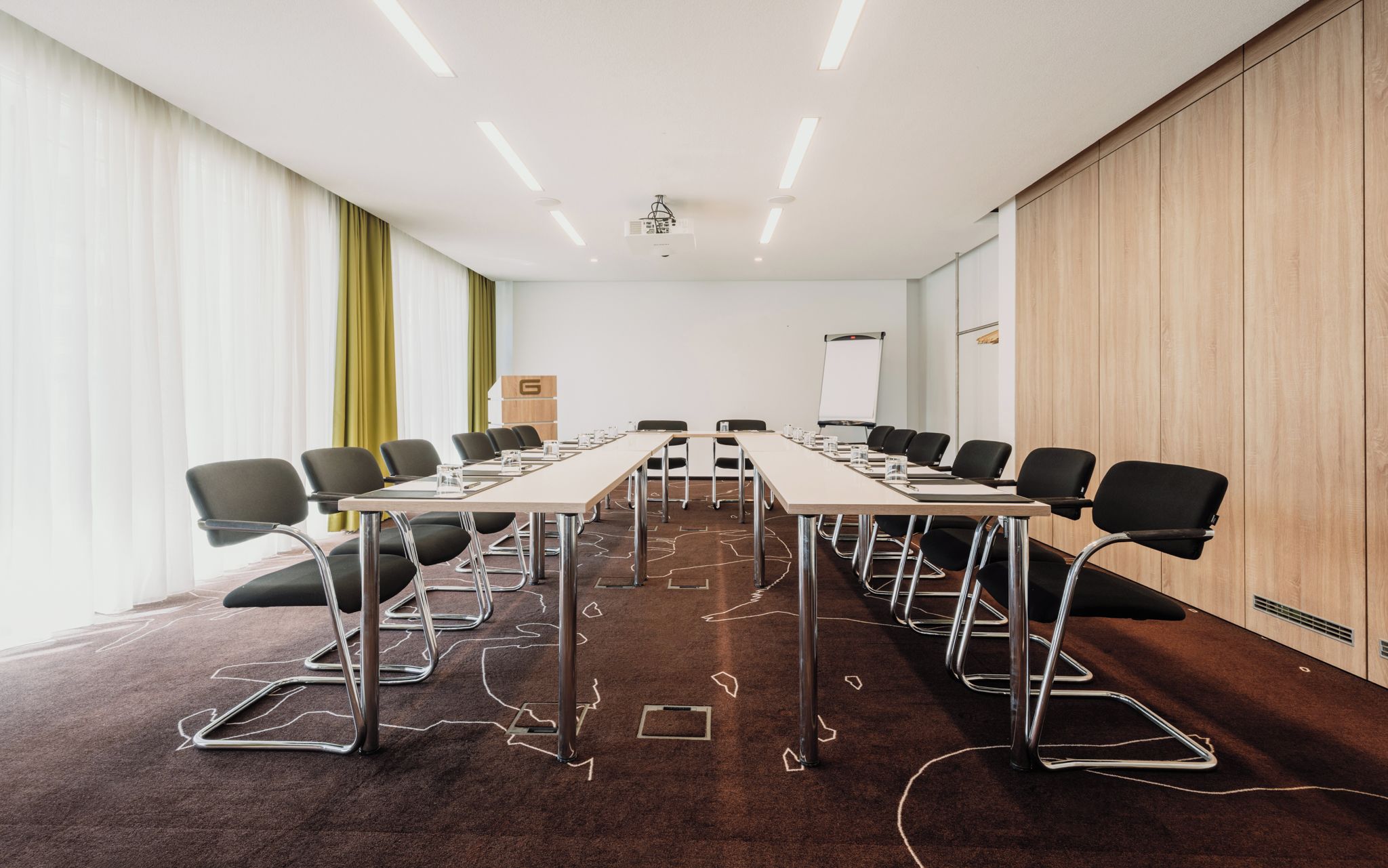 A conference room with a long table, chairs, a projector, and a whiteboard.