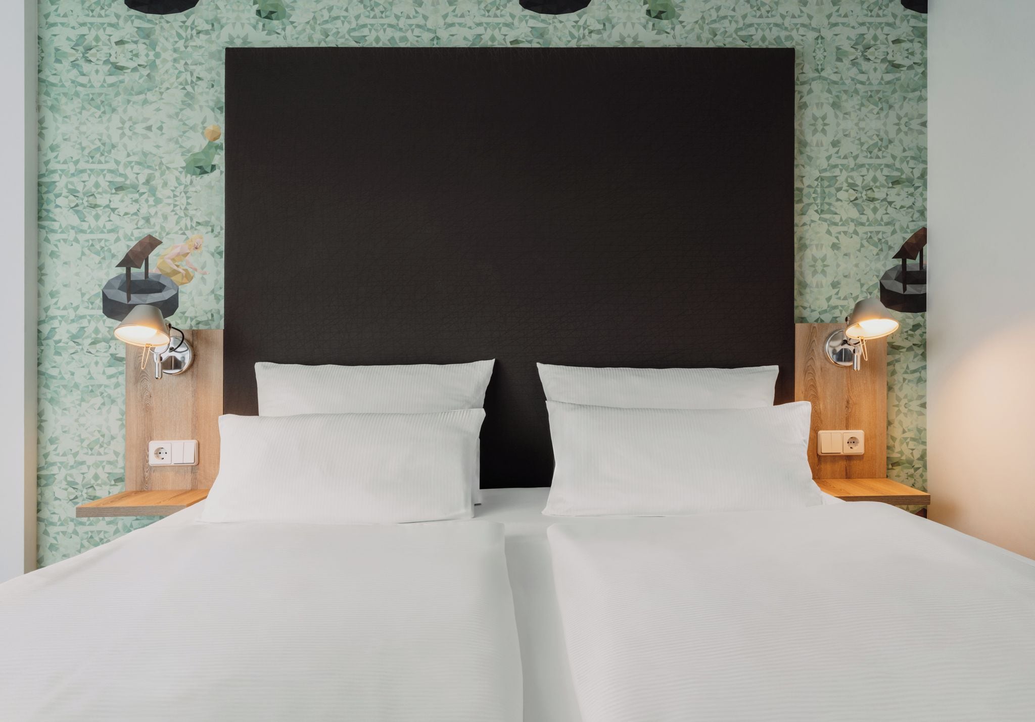 A double bed with a dark headboard and two bedside lamps.