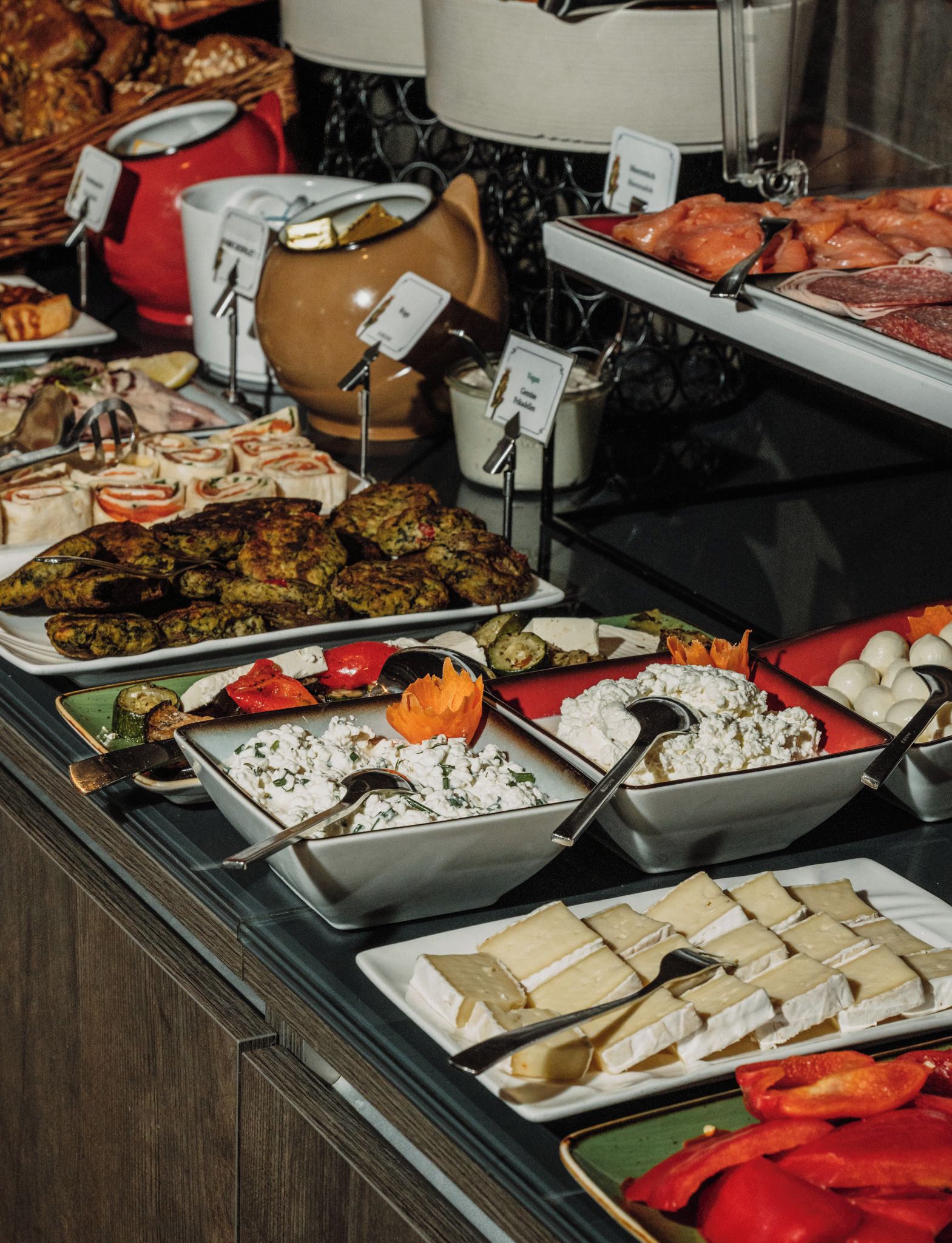 En buffet med forskellige retter, herunder kød, oste og grøntsager.