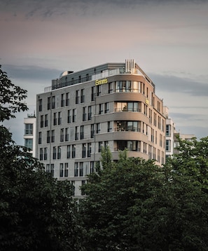 A multi-story hotel with a modern design, featuring balconies and large windows. - Grimms Potsdamer Platz (Berlin)