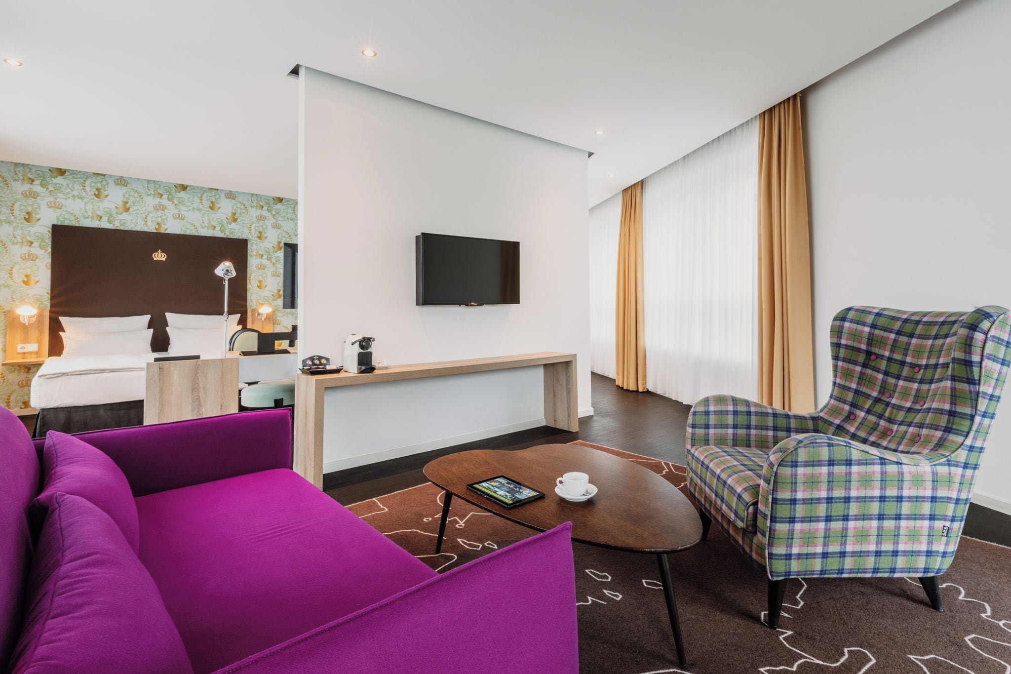 Una habitación de hotel con cama, escritorio, televisor, mesa de centro y una silla.