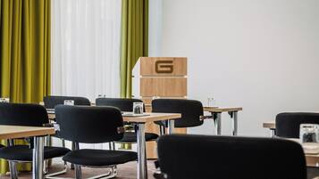 A conference room with a projector, a wooden cabinet with a letter 'G', and black chairs around tables.