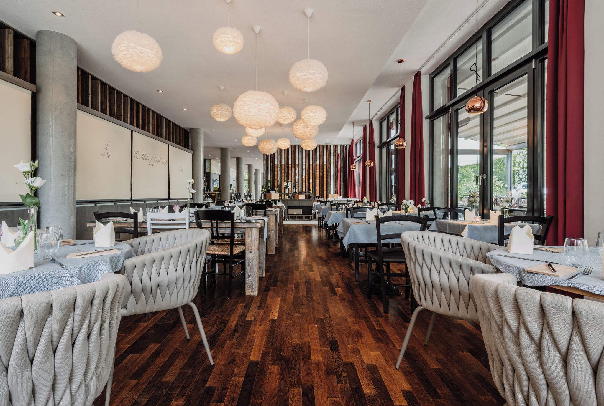 A spacious restaurant with high ceilings, wooden flooring, and multiple dining tables.