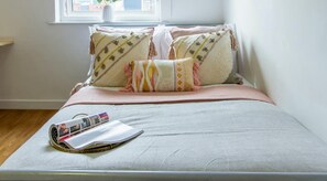 A neatly made bed with a magazine, pillows, and a window view. -  For Students Only Ensuites in Birmingham (Birmingham)
