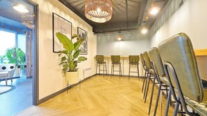 Une salle de conférence dotée d’un plancher en bois, d’une grande plante en pot et d’un luminaire suspendu.