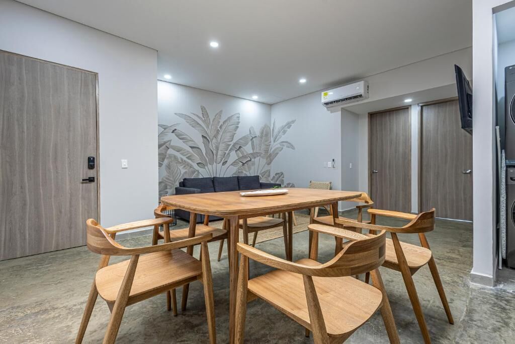 A modern dining area with a round wooden table and matching chairs, a sofa, and a large wall mural.