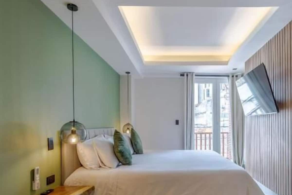 Un dormitorio moderno con tragaluz, cama, mesita de noche y vistas al exterior.