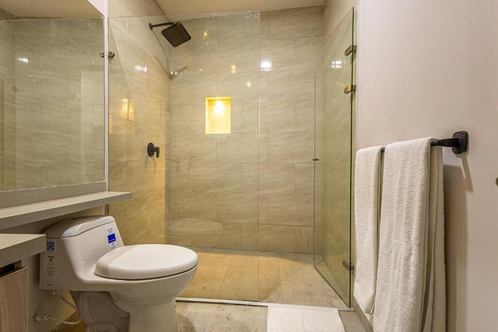 A modern bathroom with a toilet, a glass shower enclosure, and a towel rack.