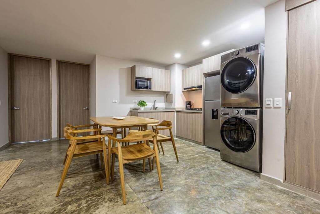 A compact kitchen with a dining area, built-in appliances, and a large washing machine.