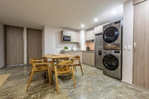 A compact kitchen with a dining area, built-in appliances, and a large washing machine. - De la Cruz Studio apartments (Cartagena)