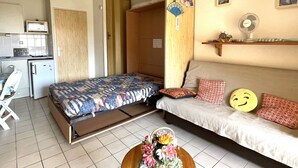 Una habitación compacta con cama, kitchenette pequeño, zona de comedor y baño.