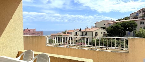 A balcony with a view of the sea and neighboring buildings.
