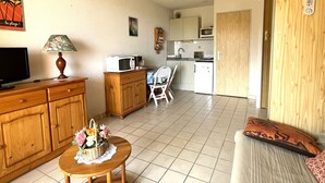 Un espacio habitable compacto con kitchenette, comedor y sofá.
