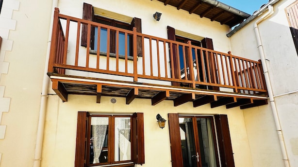 Un edificio a due piani con un balcone, un tavolino e una sedia.