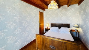 Una camera da letto con un letto di legno, carta da parati floreale, soffitto in legno e lampadario.