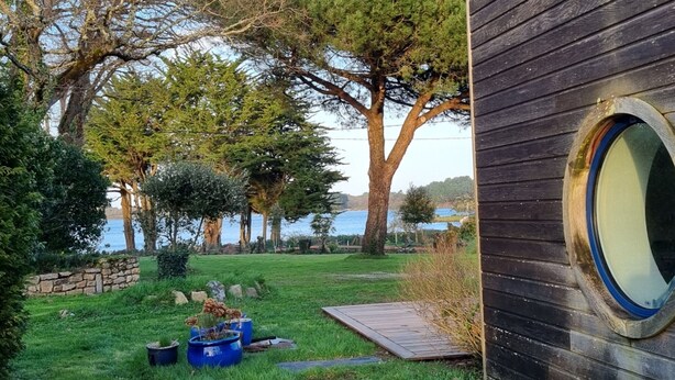 Ein Garten mit Holzterrasse, Steinmauer und einem großen Baum.