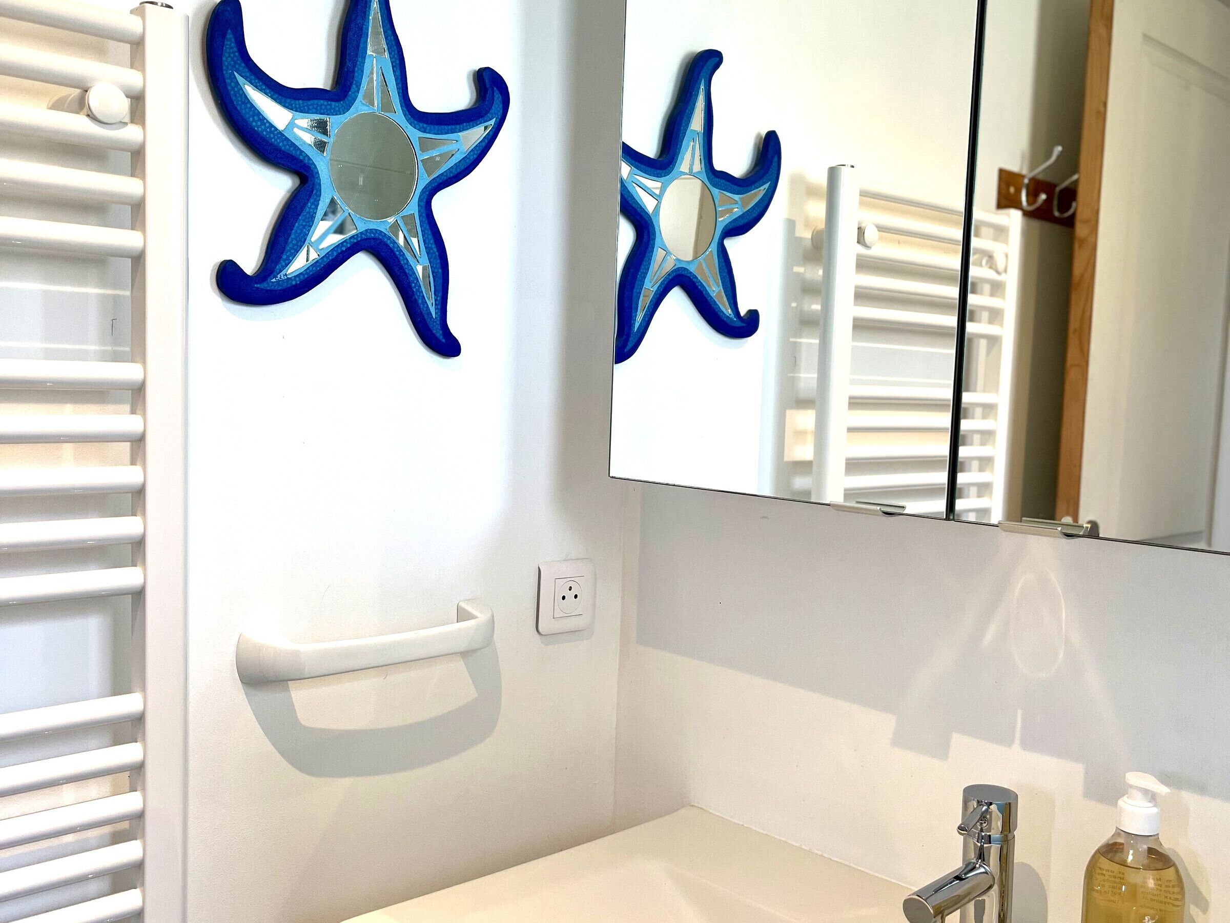 A bathroom with a white sink, a mirror, and two blue star-shaped wall decorations.