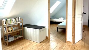Een kamer met een schuine kap, een houten boekenkast, een witte kast en een bed met een gestreept kussen.