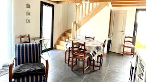 Een eetruimte met een houten tafel en stoelen, een trap en een deur naar buiten.