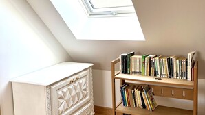 Een kamer met dakraam, een witte kast en een boekenplank vol boeken.