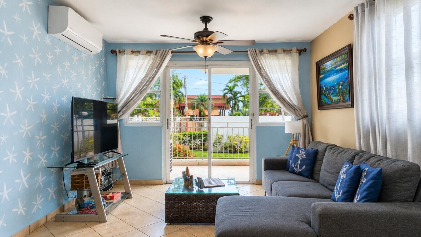 A living room with a television, sofa, and a glass coffee table.