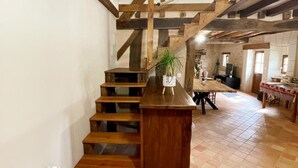 A rustic interior with a wooden staircase leading to a dining area. - Charming country house in Loire - pers. (Monthodon)