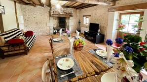 A rustic dining area with exposed wooden beams, a fireplace, and a television in the background. - Charming country house in Loire - pers. (Monthodon)