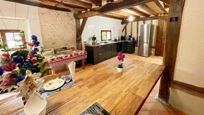 A kitchen with wooden beams, a dining table set for two, and a refrigerator. - Charming country house in Loire - pers. (Monthodon)