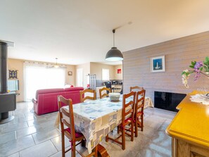 A dining area with a table set for four, wooden chairs, a yellow counter, and a kitchen in the background. - House near ocean - 6 guests (Mimizan)