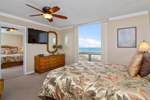 A bedroom with a large bed, a ceiling fan, a dresser, a TV, a window with a view of the ocean, and a painting on the wall. - ST 1056 Your Perfect Beach Escape w/Beach Service (Destin)