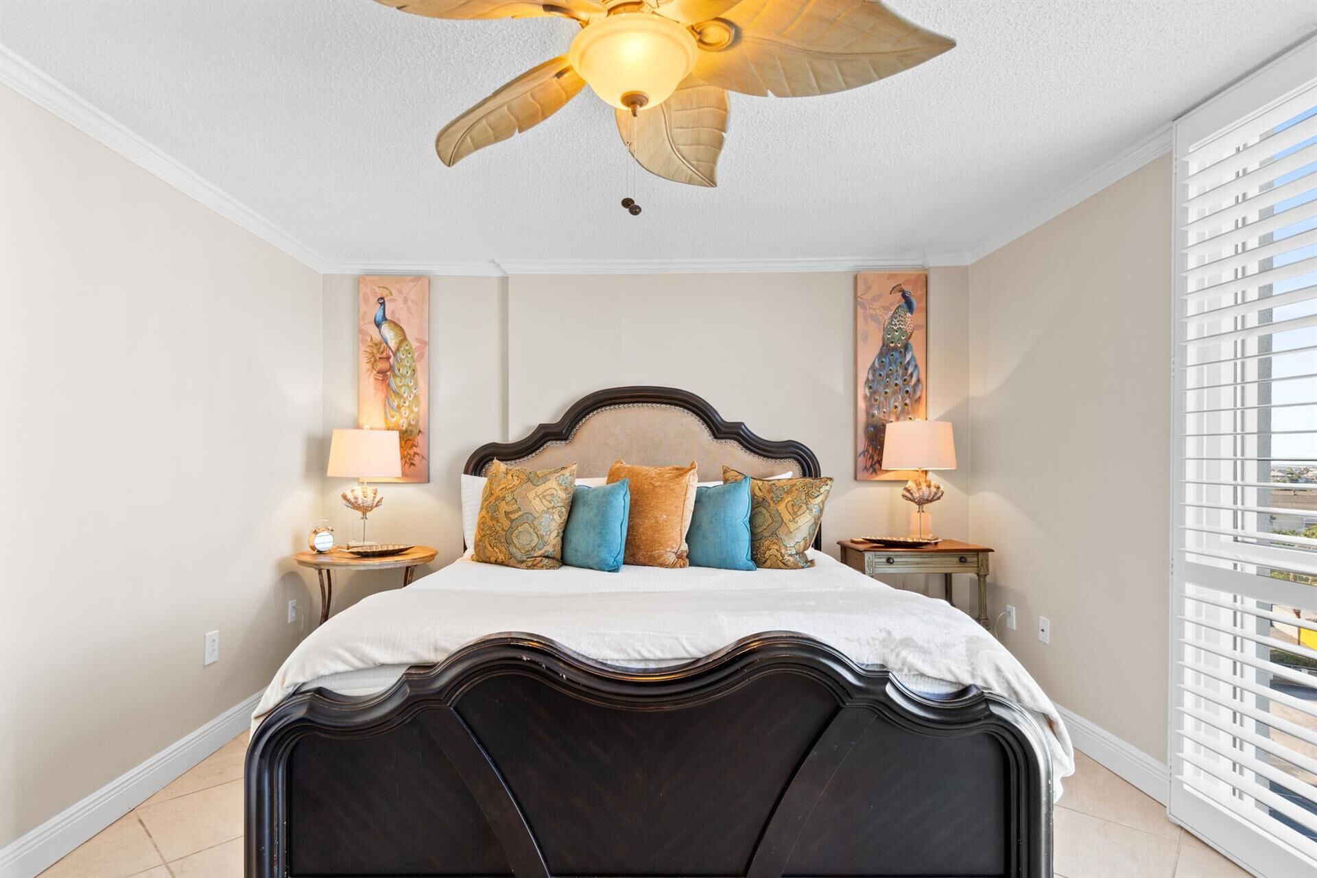Ein Schlafzimmer mit einem Bett aus dunklem Holz, dekorativen Kissen, zwei Nachttischen mit Lampen und Deckenventilatoren.