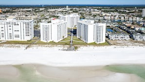 A high-rise hotel with a central courtyard, located near a beach with a view of the ocean and a marina.