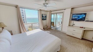 Une chambre d’hôtel avec un lit, une télévision, un bureau et une vue sur la plage.
