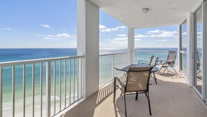 Ein Balkon mit Blick auf den Ozean, einem Tisch und zwei Stühlen.