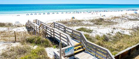 A wooden boardwalk leading to a beach with clear skies and calm waters.