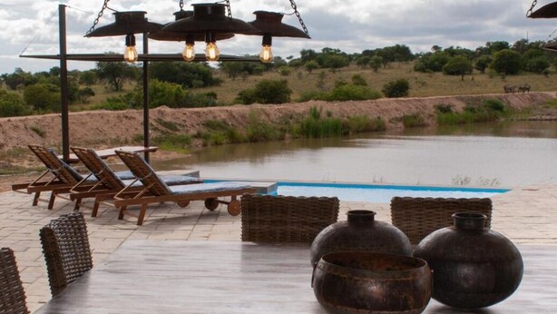 Un área de estar al aire libre con sillones reclinables y una piscina.