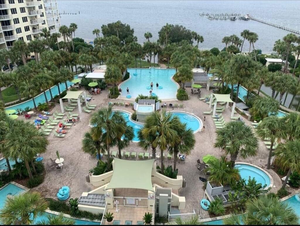 A resort with multiple swimming pools, palm trees, and a view of the sea.