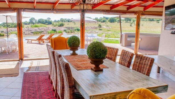 Un espace extérieur aménagé pour les repas, avec des meubles en osier, une table en bois et une vue sur le paysage.