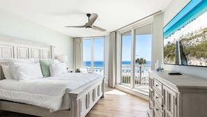 A bedroom with a large bed, a ceiling fan, a TV, and a view of the beach. - Luxurious Silver Beach 306E - Gulf Front End unitSleeps 10 w/3 ensuite bathrooms (Destin)