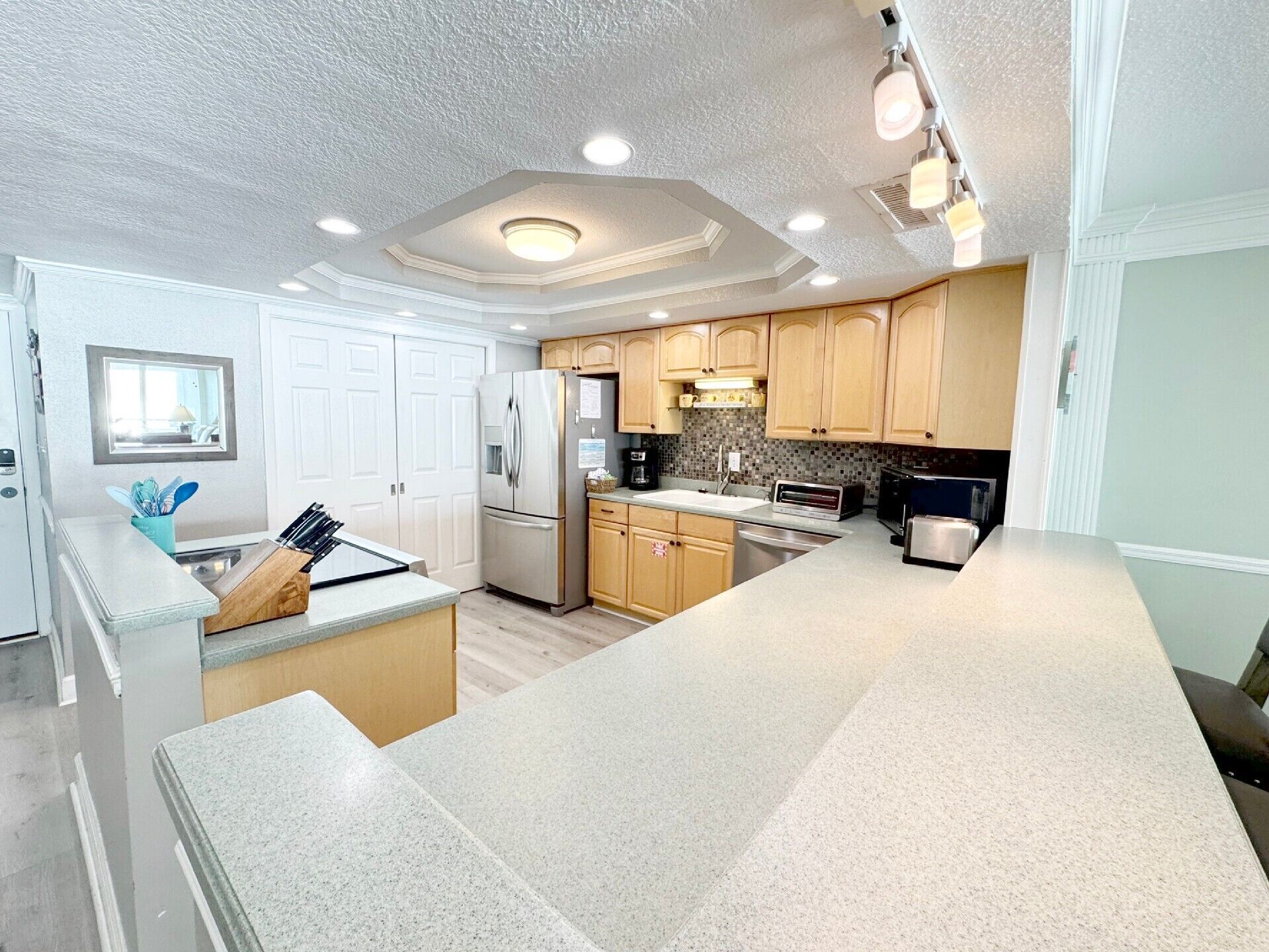 A modern kitchen with a central island, built-in appliances, and a large window.