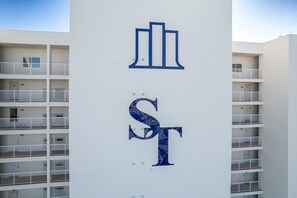 A building with a white facade and a large blue 'ST' sign. - Splendid Views from Shoreline Towers 3112 (Destin)
