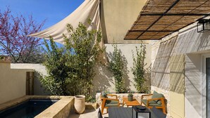 A poolside area with a table and chairs, a pergola, and potted plants. - Petit Mas des Cigales Saint-Rémy de Provence (Saint-Rémy-de-Provence)