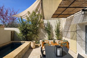 Ein Poolbereich mit Tisch und Stühlen, einer Pergola und Topfpflanzen.