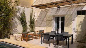 An outdoor patio with a pool, wooden and metal furniture, and a stone wall. - Petit Mas des Cigales Saint-Rémy de Provence (Saint-Rémy-de-Provence)