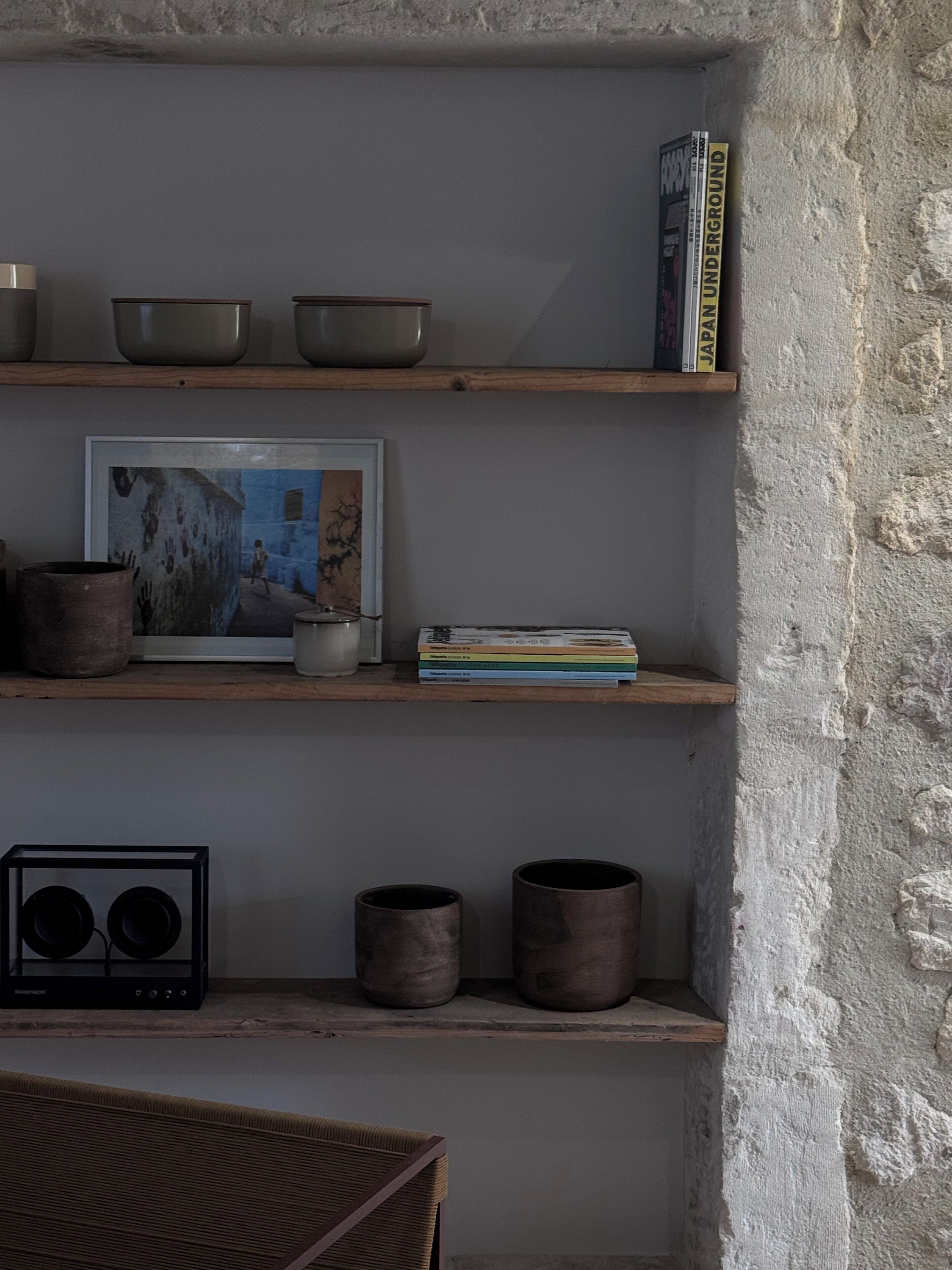 A shelf with bowls, a framed picture, and books.