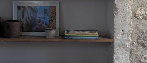 A shelf with bowls, a framed picture, and books.
