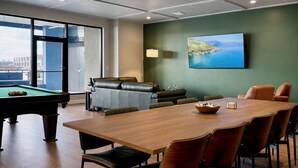 A conference room with a pool table, leather sofa, and a dining table with chairs. - NuLu Skyline 5BR Penthouse and Rooftop Spa (Louisville)