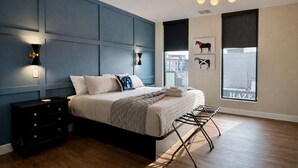 A modern bedroom with a bed, bedside tables, wall-mounted lights, and artwork. - NuLu Skyline 5BR Penthouse and Rooftop Spa (Louisville)