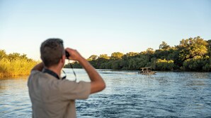A man taking a photo of a boat on a river. - Simanya River Lodge (Nkurenkuru)